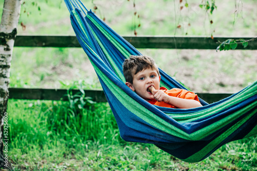Little boy with ice-cream in hammock in village outdoor