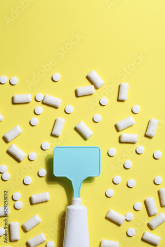 Titanium dioxide, E171, dangerous additive concept. gum, pills, toothpaste or cream and sign with space on yellow background. copy space photo