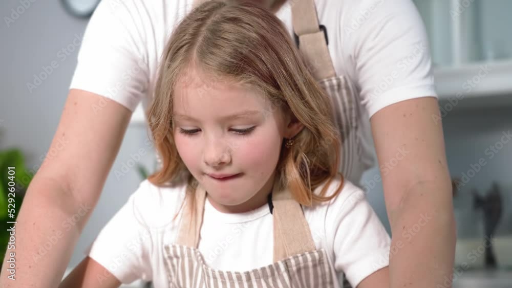 helping parents, adorable little girl helps her mom to roll out dough for homemade pastries with a rolling pin at home in the kitchen helping parents, adorable little girl helps her mom to roll out dough for homemade pastries with a rolling pin at home in the kitchen