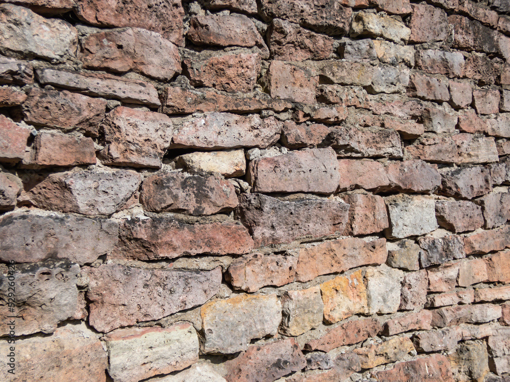 Fototapeta premium View of empty, old white, pink and grey brick wall background with copy space. A deteriorating old brick wall outdoors in sunlight