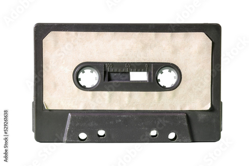An old vintage cassette tape from the 1980s (obsolete music technology). Black plastic body, old worn textured paper label. Isolated.
