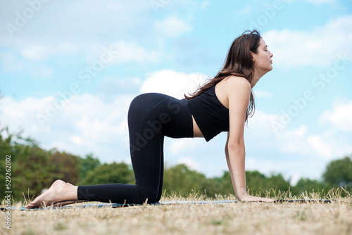 Portrait of young caucasian woman doing yoga on grass in a park. © Jorge Elizaquibel