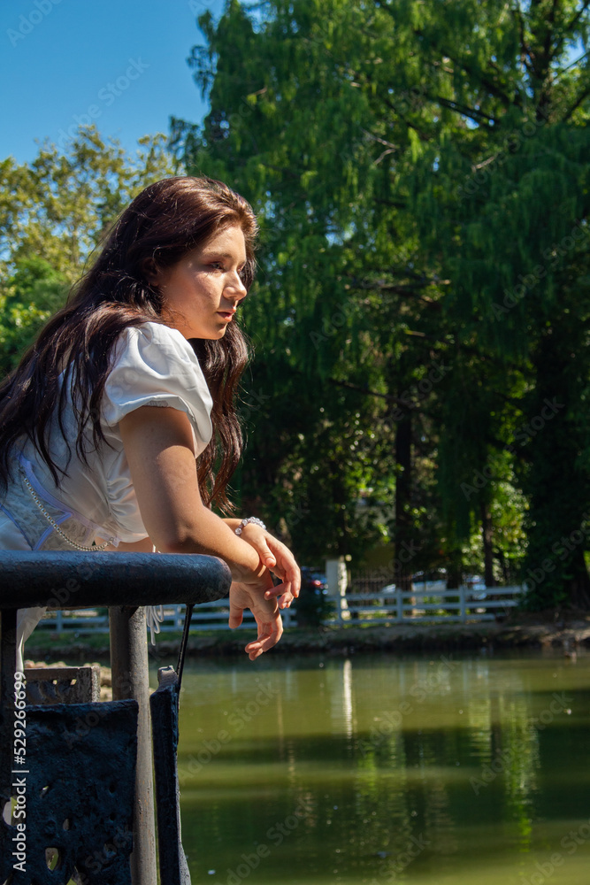 Naklejka premium A beautiful girl in a white dress by the lake