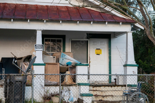 Condemned home with waste and materials on porch