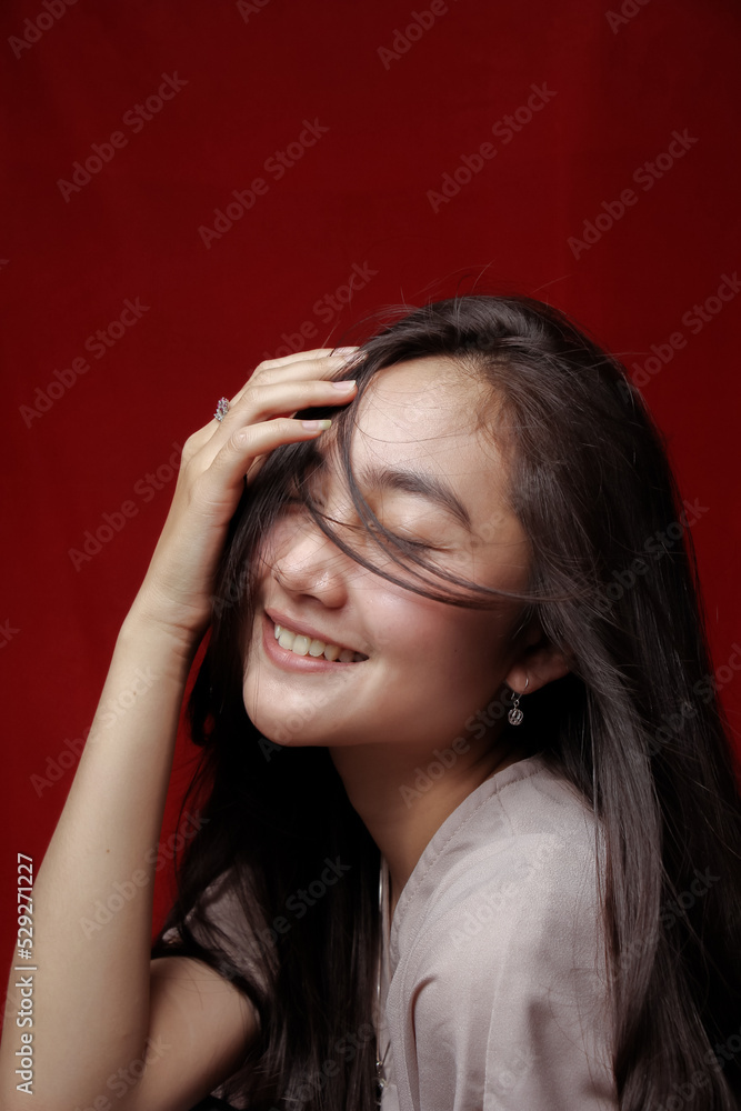 Obraz premium Asian woman taking photo on a red background. Happy Asian woman. Beautiful asian woman with long and straight hair.