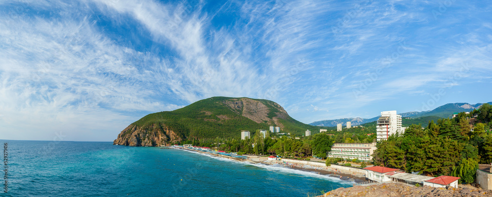 View from the Kuchuk-Ayu rock to the green mountain Ayu-Dag at the Partenit village. A bay on the Black Sea with a beach and a blue sky with cirrus clouds at background. Crimea,Ukraine