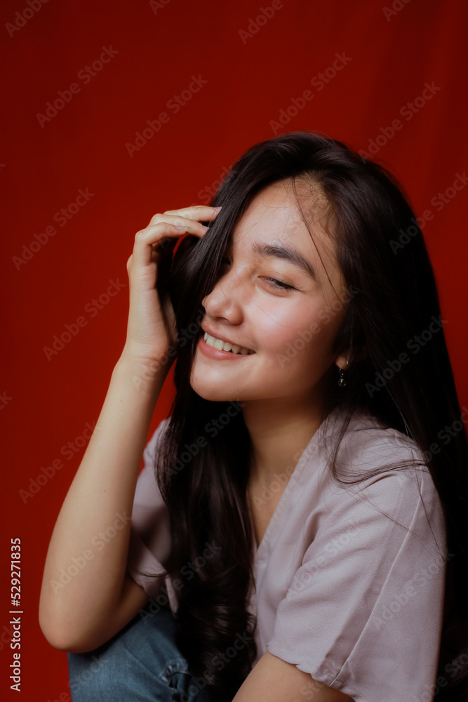 Fototapeta premium Asian woman taking photo on a red background. Happy Asian woman. Beautiful asian woman with long and straight hair.