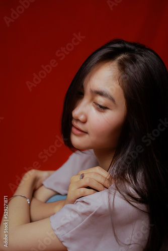 Asian woman taking photo on a red background. Happy Asian woman. Beautiful asian woman with long and straight hair. © ajiilhampratama
