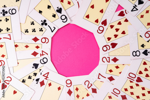 A deck of playing cards laid out in a circle with copy space or workspace mockup and white round frame place.. White cards with red and black suits on a pink background for advertising, presentations