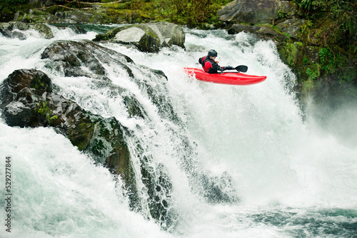 Whitewater kayaker descending waterfall in forest