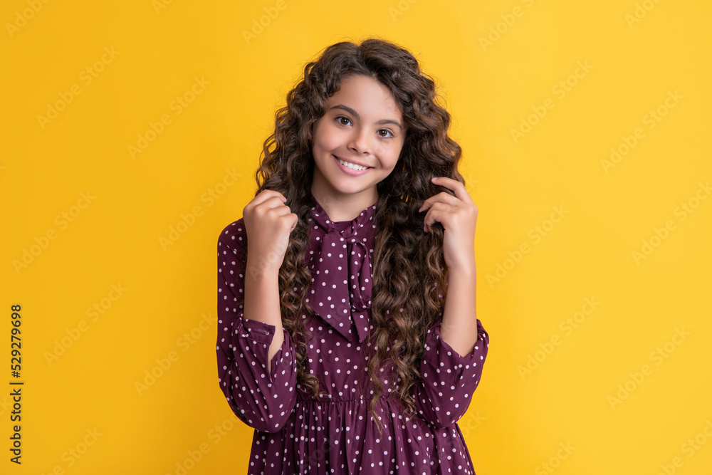 happy child with long brunette frizz hair on yellow background happy child with long brunette frizz hair on yellow background