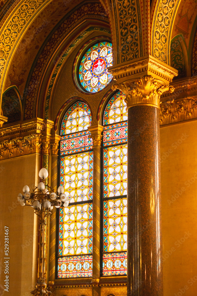 All stained glass windows are in the Parliament House, Budapest, Hungary. Arches, gold leaf trim, painted wallpaper surround windows.