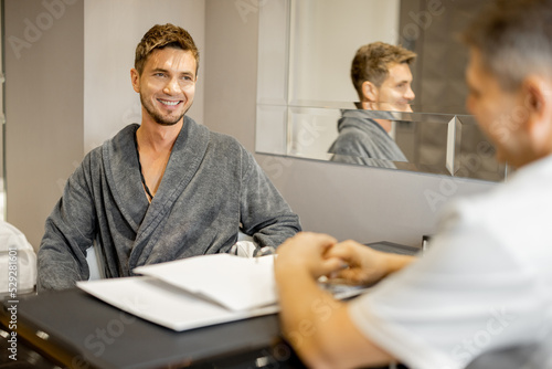 Man in a bathrobe on appointment with senior therapist in luxury medical spa salon. Consultation with a doctor before beauty procedures photo