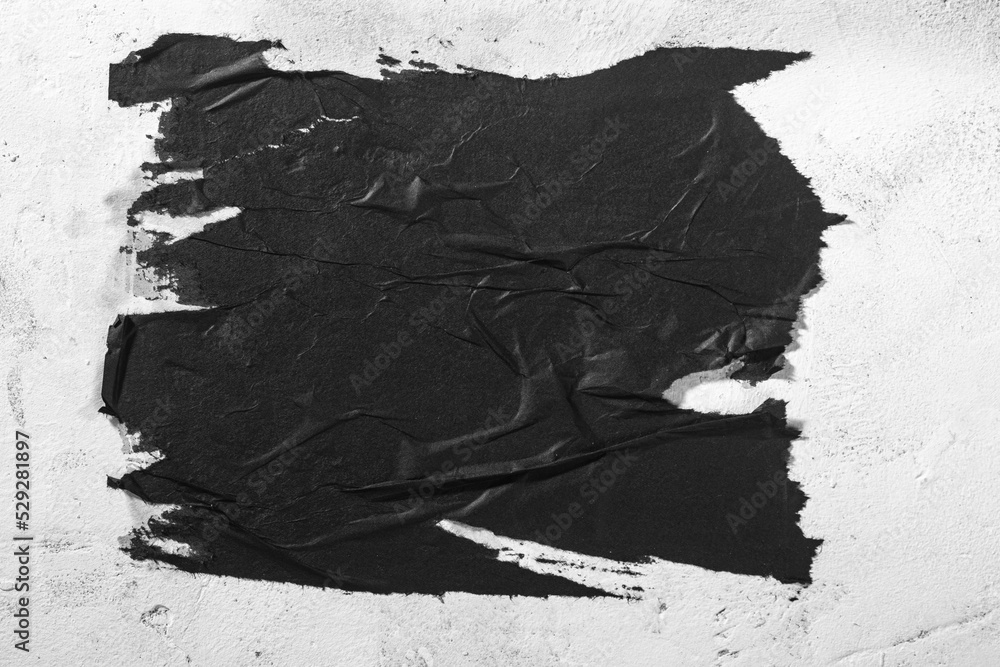 Scraps of black paper on a white wall. - obrazy, fototapety, plakaty 