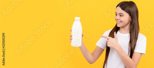 cheerful child point finger on dairy beverage product. teen girl going to drink milk. Horizontal poster of isolated child face, banner header, copy space.