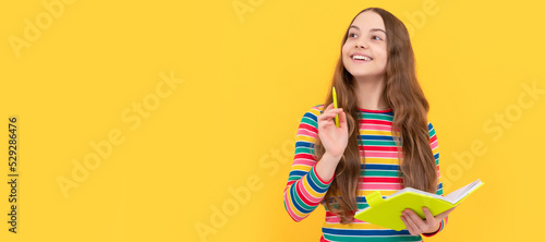 Flash of genius. Happy girl hold copybook pointing pen up. Child genius yellow background. Horizontal isolated poster of school girl student. Banner header portrait of schoolgirl copy space.