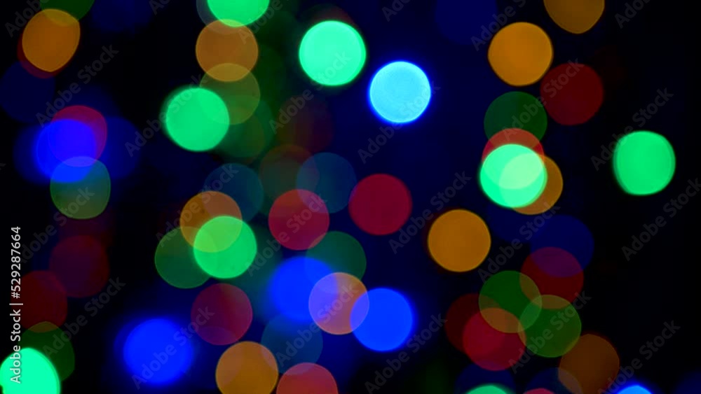 Multi-colored flashing lights of a garland in defocus on a black background Multi-colored flashing lights of a garland in defocus on a black background