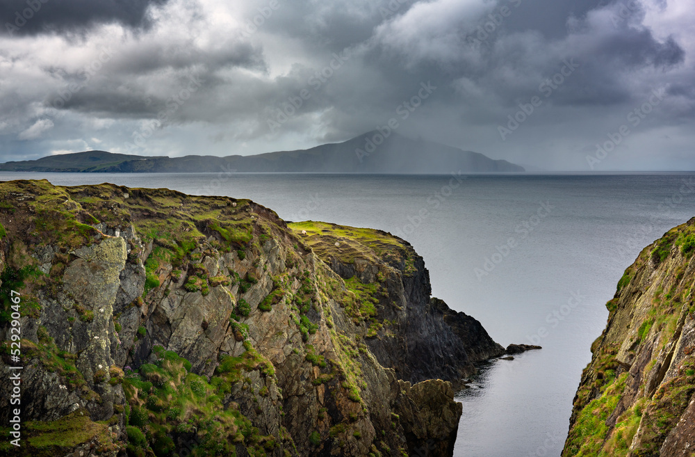 Cliffs on the west coast of Achill Island. It is a popular route along the Wild Atlantic Way. Clouds and rain on the horizon. Cliffs on the west coast of Achill Island. It is a popular route along the Wild Atlantic Way. Clouds and rain on the horizon.