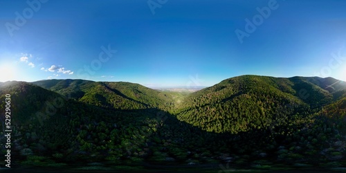 360 aerial drone view in the Wuenheim valley with the plain below with the Alsace village of Soultz-Haut-Rhin  at summer sunset