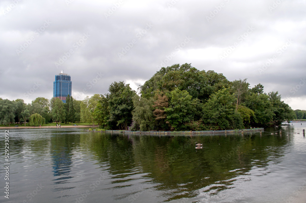 Lake with an island and a skyscraper in London's Hyde Park