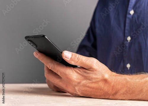 Man hands with phone. Male sitting at table and using smartphone for work, personal interests.