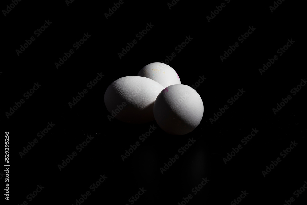 tres huevos blancos de gallina, sobre fondo negro tres huevos blancos de gallina, sobre fondo negro