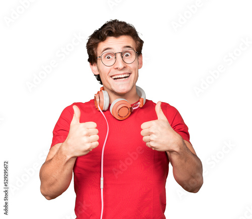 Happy young man using headphones and a smartphone with an okay gesture