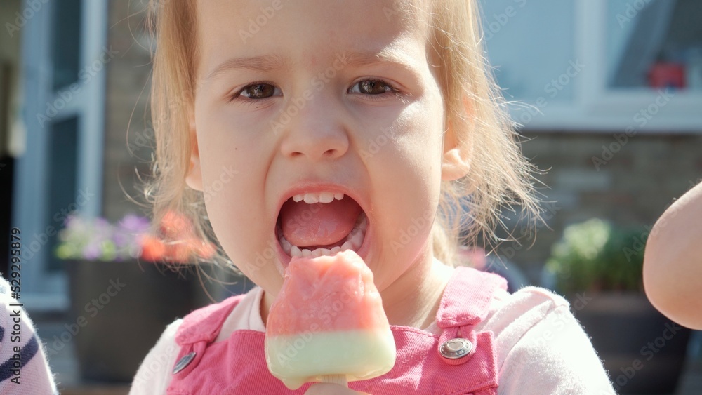 Close up portrait Girl enjoys delicious ice cream cone. Child eating watermelon popsicle. Kids Siblings snack sweets in Home Garden. Summer holiday Hot weather Sunny Day. Childhood, Food Candy Friends Close up portrait Girl enjoys delicious ice cream cone. Child eating watermelon popsicle. Kids Siblings snack sweets in Home Garden. Summer holiday Hot weather Sunny Day. Childhood, Food Candy Friends