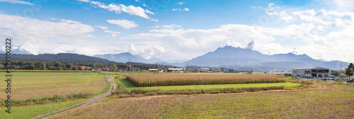 Swiss countryside panorama. Beautiful touristic summer scenery in Switzerland. Farms, agricultural land, corn fields and view to Mount Pilatus in front of blue and cloudy sky. Selective focus. photo
