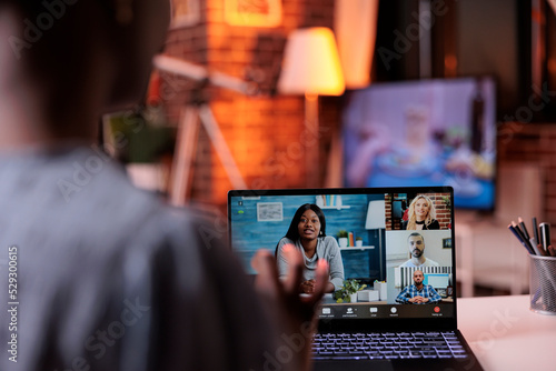Businesspeople having conversation on online business meeting, telecommunications and remote teamwork concept. Businesswoman chatting with coworkers using videocall software and laptop, back view