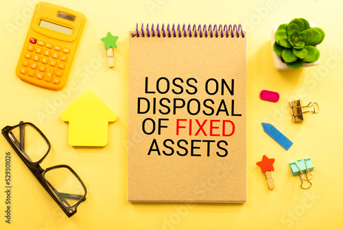 Loss on disposal of fixed assets label on notepad with laptop and smartphone on wooden table. photo
