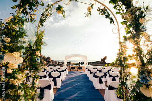 Chairs arranged for ceremony seen through wedding arch photo