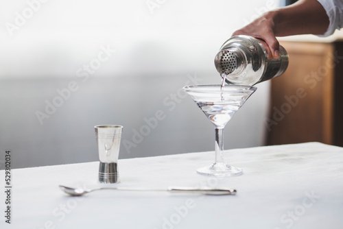 Cropped image of woman hand pouring alcohol in martini glass photo