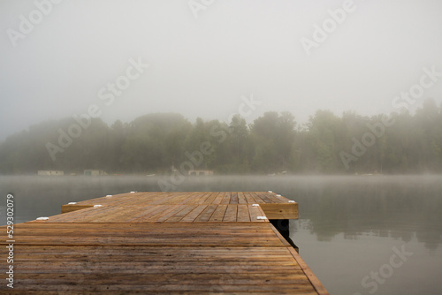 Wooden pier over lake against sky during foggy weather photo