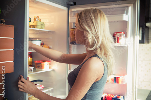 Side view of teenage girl looking in refrigerator at kitchen