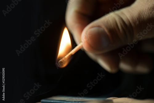 Cropped hand holding burning matchstick in darkroom