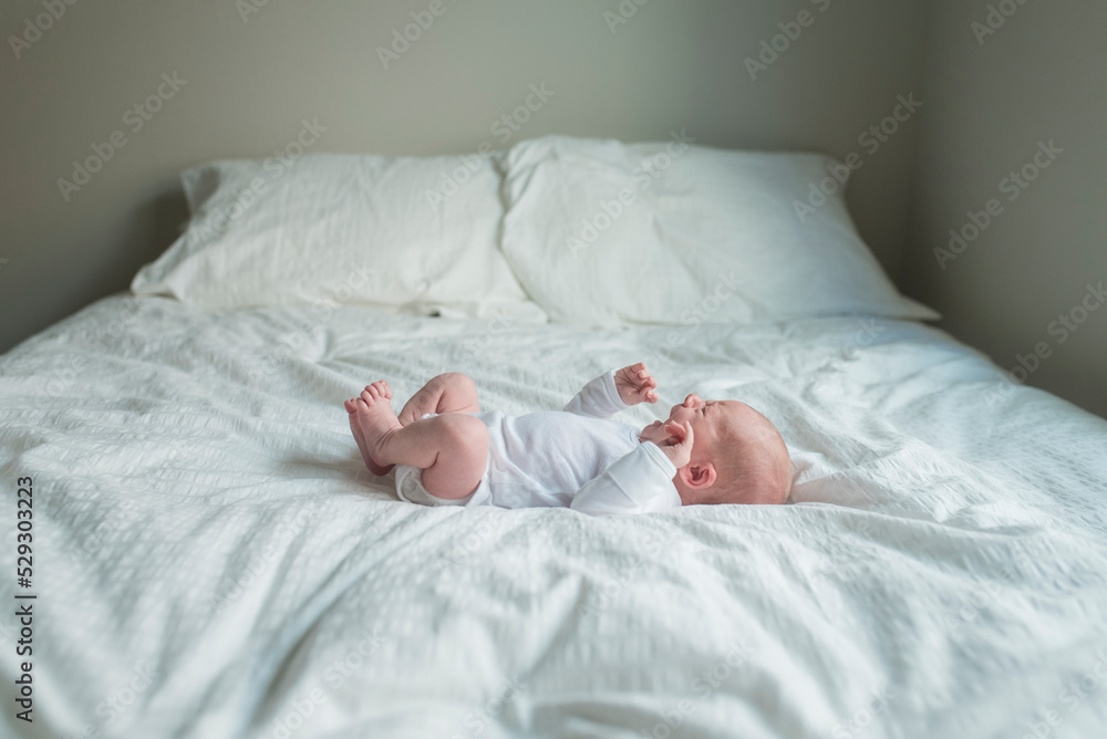 Side view of newborn baby boy crying while lying in bed at home Side view of newborn baby boy crying while lying in bed at home