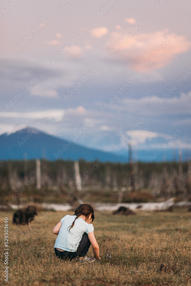Rear view of girl crouching on field against sky Rear view of girl crouching on field against sky