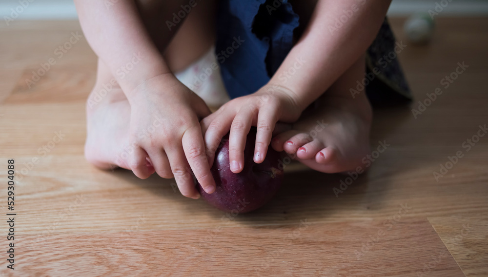 Low section of girl playing with apple at home Low section of girl playing with apple at home