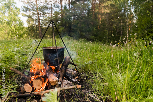 Food being cooked in container on campfire at forest photo