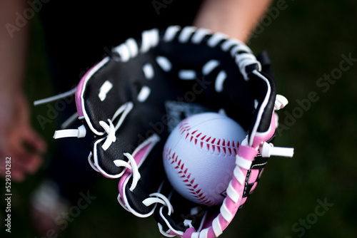 Cropped hand of girl wearing baseball glove with ball photo