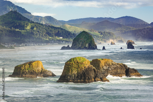 Rocks in sea against mountains at Ecola State Park photo