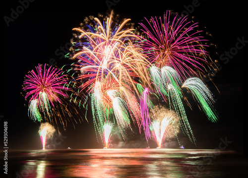 Multi coloured fireworks exploding over an ocean in the night sky. photo