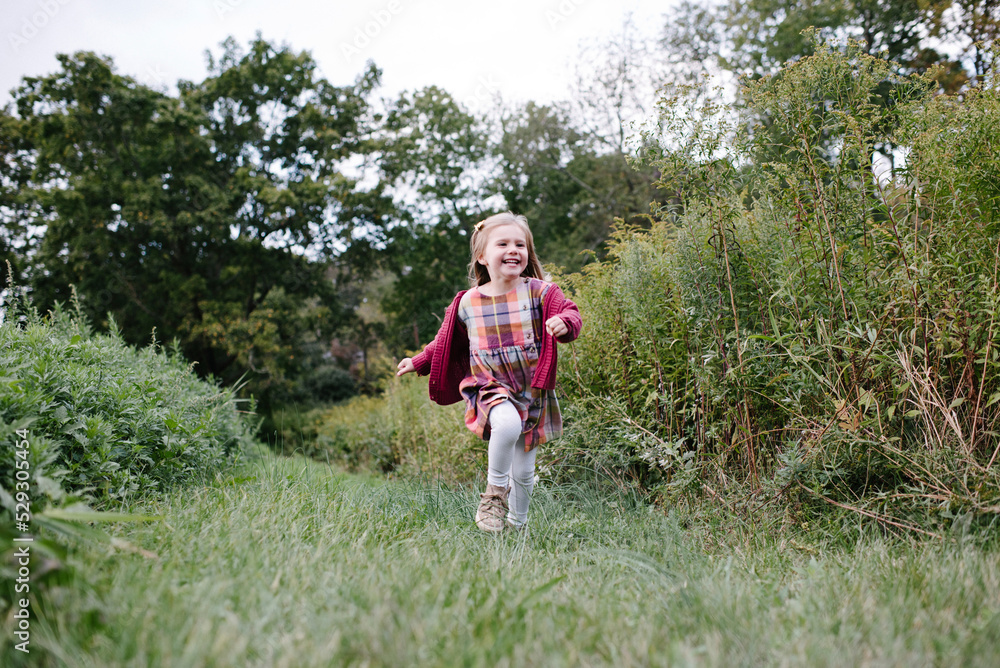 Full length of cheerful girl running on field at park Full length of cheerful girl running on field at park