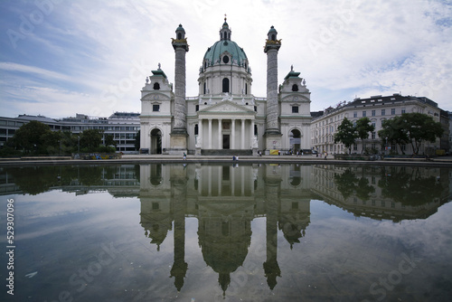 Karlskirche reflecting on pond against sky photo