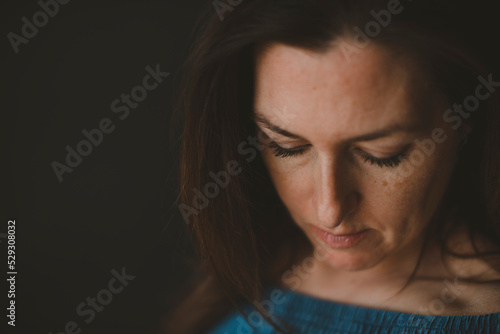 Close-up of thoughtful woman looking down against black background photo