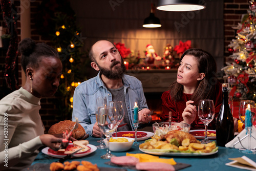 Friends chatting at christmas home party  couple talking at festive dinner table  diverse people eating traditional xmas food. Man and woman having conversation  celebration winter holiday