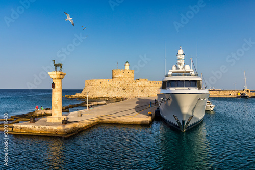 Mandraki port with deers statue, where The Colossus was standing and fort of St. Nicholas. Rhodes, Greece. Hirschkuh statue in the place of the Colossus of Rhodes, Rhodes, Greece