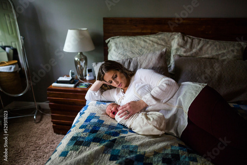 High angle view of mother lying by sleeping newborn son on bed at home photo