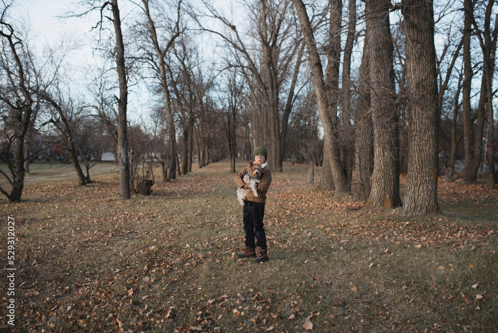 Portrait of boy carrying dog while standing on field at park during sunset Portrait of boy carrying dog while standing on field at park during sunset